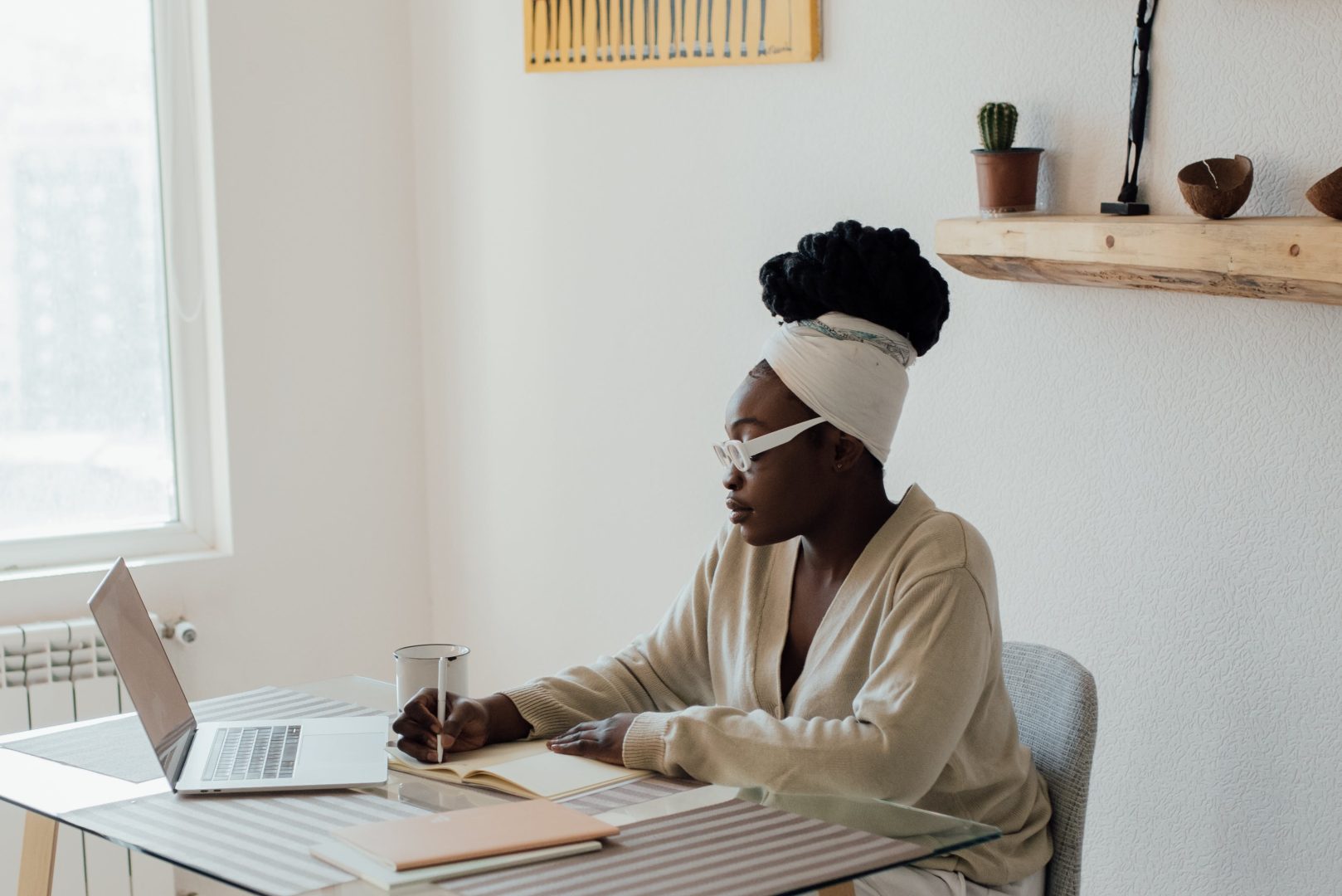 A woman working on her laptop while enjoying a cup of coffee at a table.
