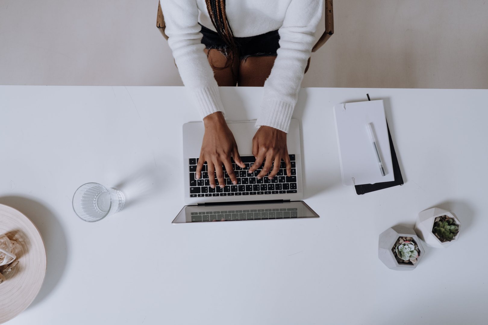 A woman focused on her laptop, typing away at a table.